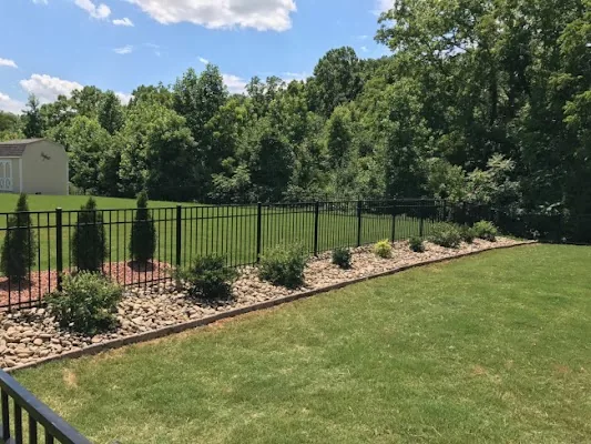 Black aluminum fence along a landscaped lawn by Timber Fencing