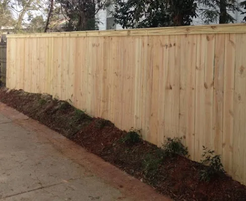 Capped wood privacy fence along a driveway by Timber Fencing